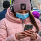 A woman wearing a face mask to protect against the coronavirus disease uses her smartphone walking on a street in Moscow on March 19, 2021.